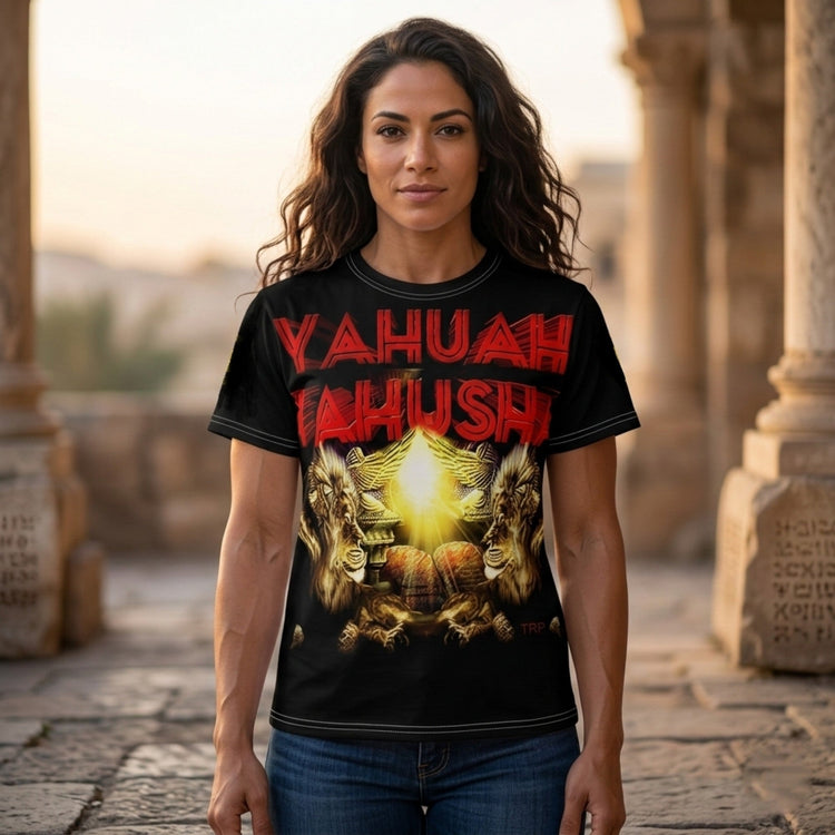 A woman with wavy hair modeling a black t-shirt featuring the red 'Yahuah Yahusha' graphic, standing outdoors in front of historic stone pillars.
