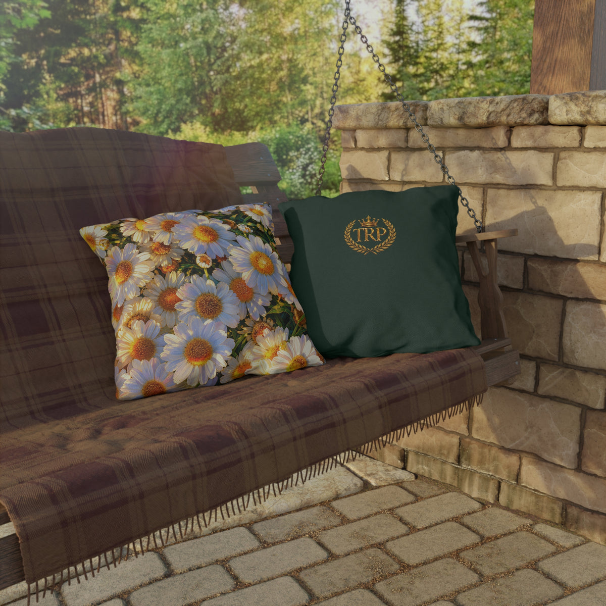 The Dawning Field medium square outdoor accent pillow with golden floral daisy print on a hanging rustic outdoor swing.