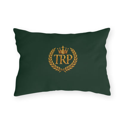 Dark green rectangular accent pillow showcasing the metallic gold TRP monogram framed by a royal crown and laurel wreath crest.