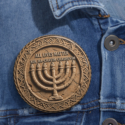 Large stone-carved menorah pinback button with geometric border and Hebrew phrase Kol Ha-Chayim Chashuvim pinned on a denim jacket.