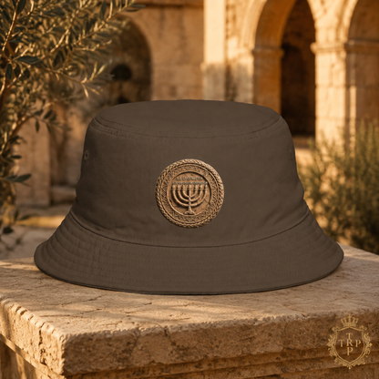 Front view of the brown All Lives Matter bucket hat with The Sevenfold Light menorah crest on an ancient stone pillar.