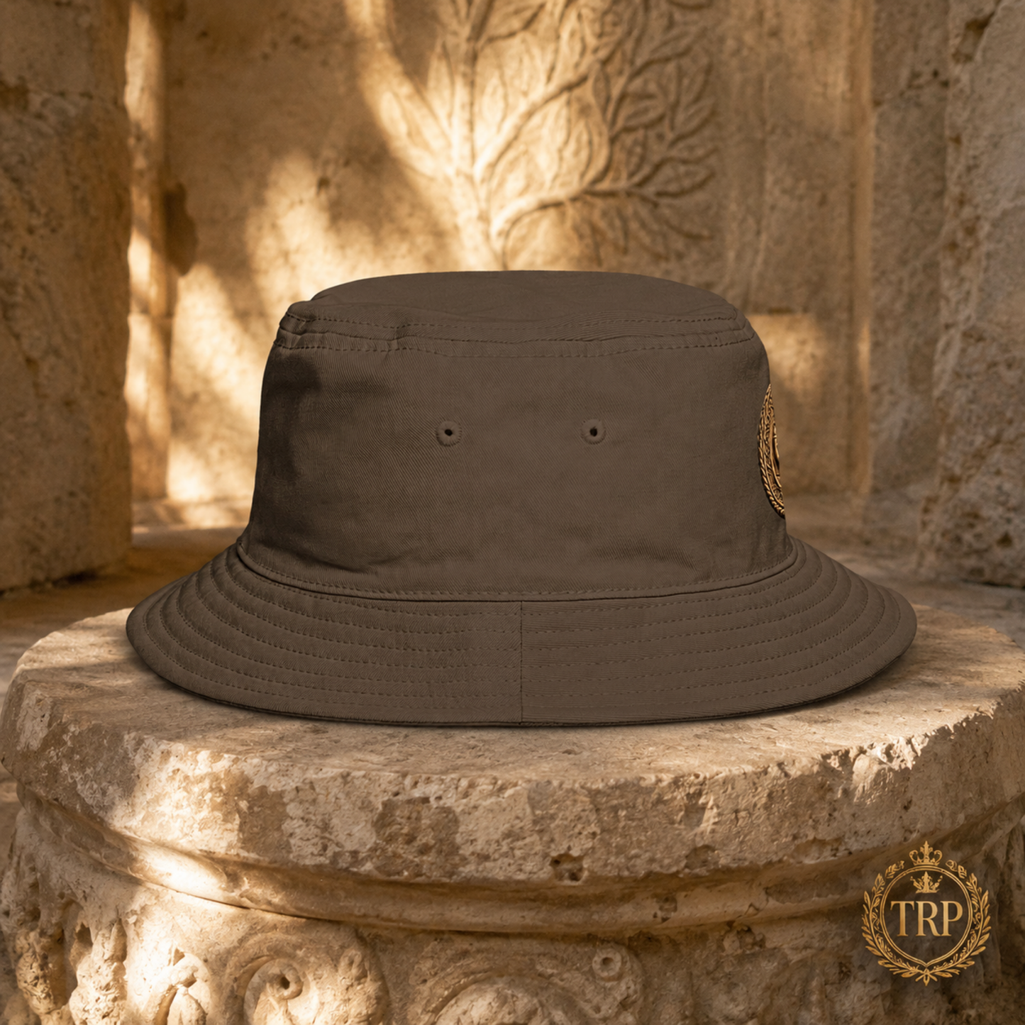 Right-side profile of the brown All Lives Matter bucket hat displayed on a rustic stone architectural column.