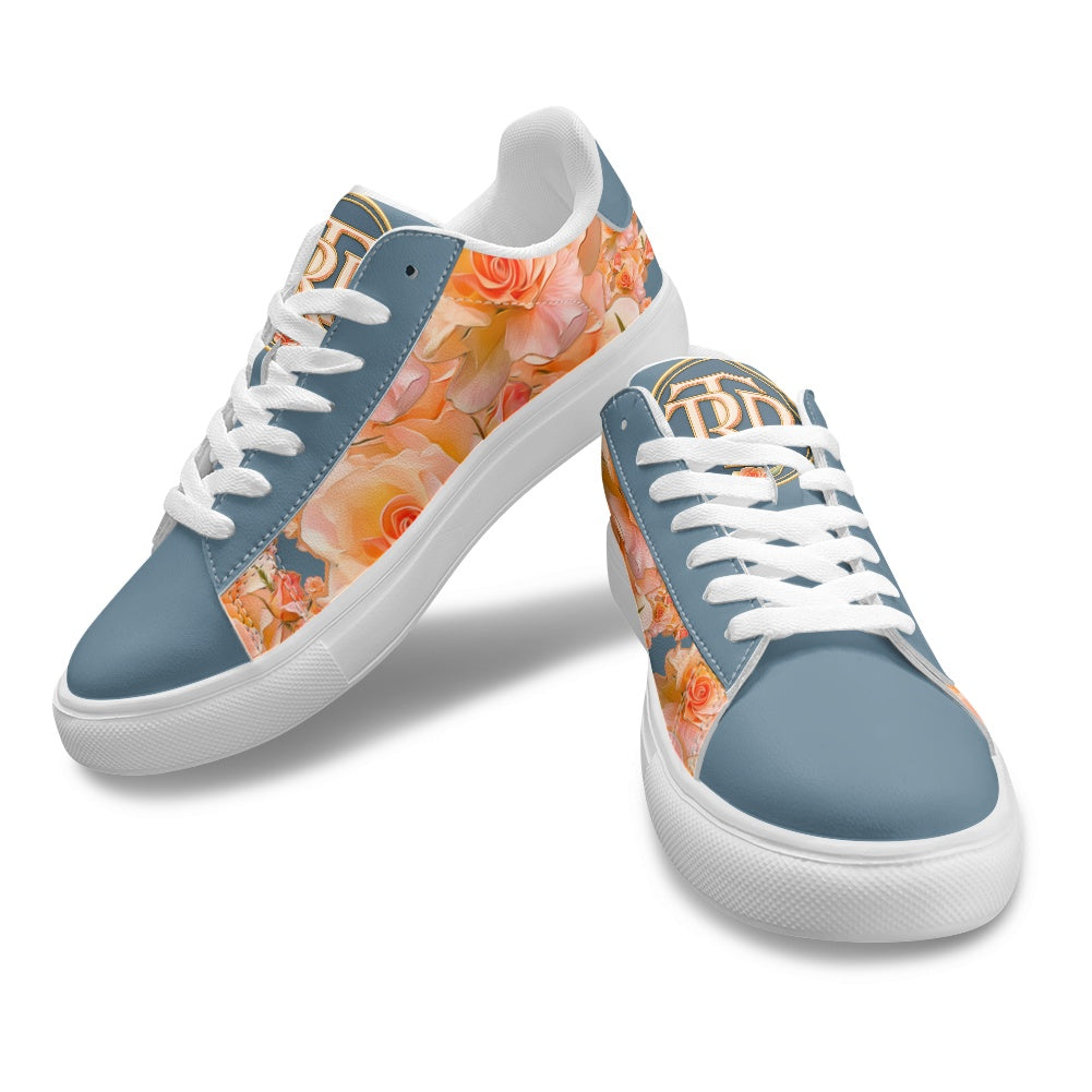 A pair of low-top sneakers with a dusty blue base, white laces, and a peach and orange floral print on the sides and heel area, shown on a white background.
