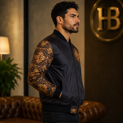 Side profile view of a man modeling the black bomber jacket, highlighting the detailed Hebrew-inspired gold geometric patterns along the sleeve.