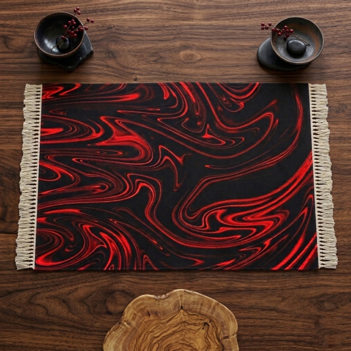 Top-down view of a rectangular black rug with vibrant red liquid-swirl patterns and white fringe, laid flat on a dark wood table with decorative bowls.