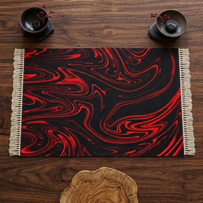 Top-down view of a rectangular black rug with vibrant red liquid-swirl patterns and white fringe, laid flat on a dark wood table with decorative bowls.
