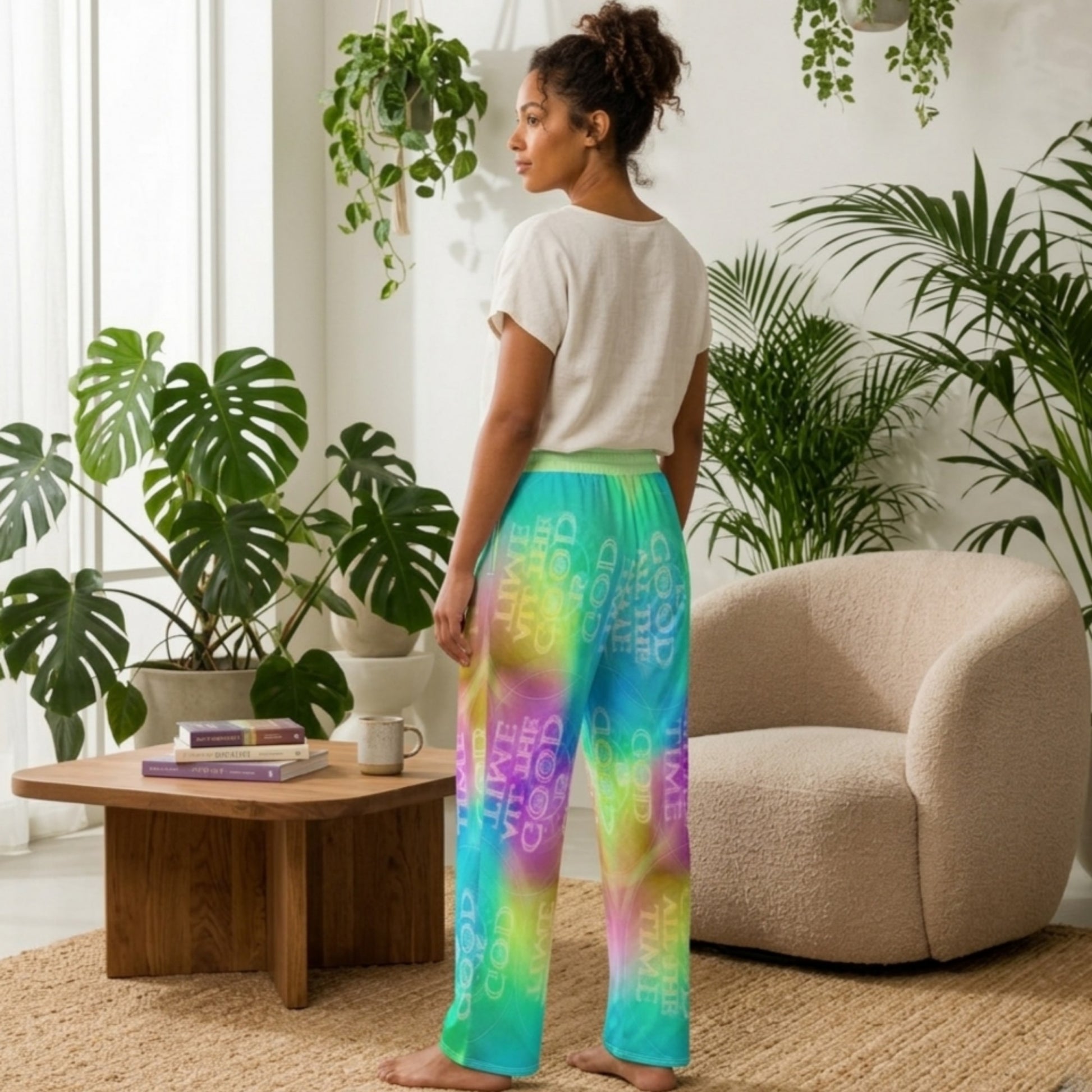 Woman wearing colorful pants in a room with plants and a coffee table.