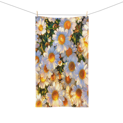 The Dawning Field hand towel hanging from a clothesline with wooden pins, showing a full vertical layout of vibrant white and gold daisy blossoms.