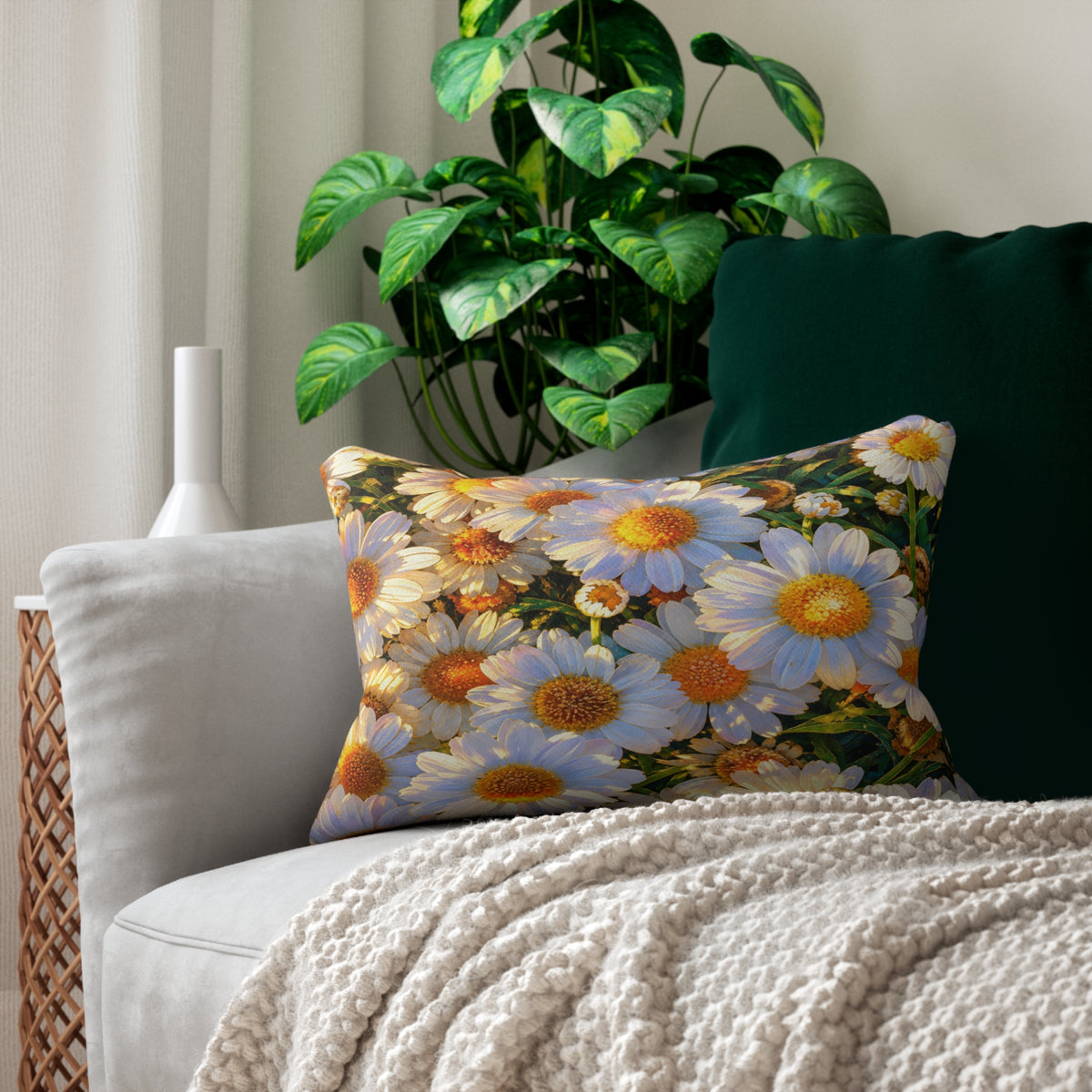 The Dawning Field Lumbar Pillow featuring white and golden daisies displayed on a cream armchair with a textured throw blanket.