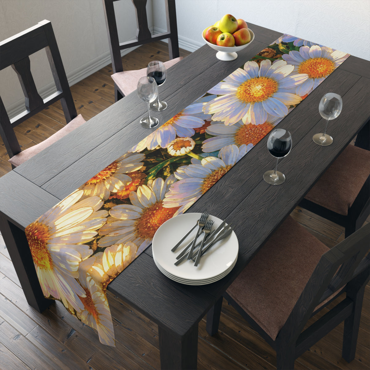 Overhead angled view of The Dawning Field daisy table runner styled on a dark wood table with place settings, wine glasses, and apples.