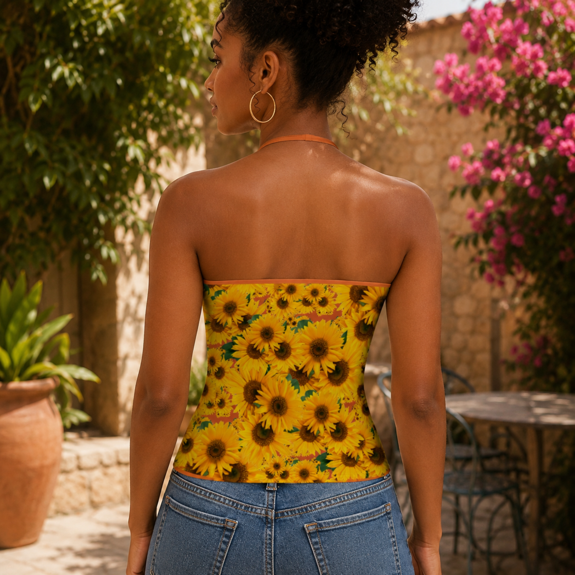A back view of a woman showcasing the fit of the sunflower print halter top with vivid red tangelo (orange-colored) trim.